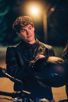 a man sitting on top of a motorcycle at night