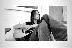 a man sitting on top of a bed holding a guitar