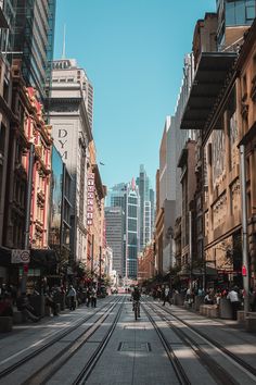 a city street lined with tall buildings and people riding bikes on the sidewalks in front of them