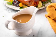 a white gravy pitcher sitting on top of a counter next to a plate of food