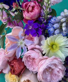 a bunch of flowers that are sitting on a blue tablecloth with watercolors