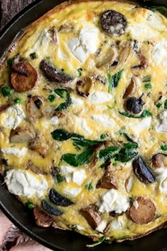 an omelet with mushrooms, spinach and feta cheese in a cast iron skillet