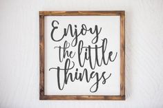 a framed sign that says enjoy the little things on it, with black lettering in a wooden frame