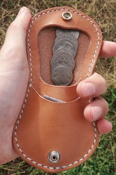 a hand holding a brown leather case with an object in it