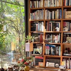 a bookshelf filled with lots of books in front of a large glass window