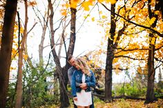 a man and woman are standing in the woods with yellow leaves on their feet as they look at each other