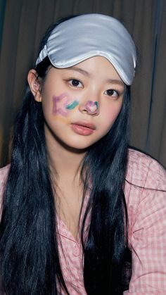 a girl with long black hair wearing a white bandana and pink checkered shirt