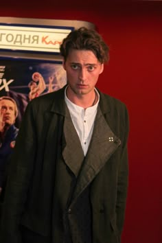 a man standing in front of a movie poster wearing a black jacket and white shirt