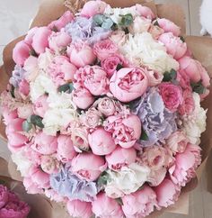 a bouquet of pink and white flowers sitting on top of a table next to other flowers