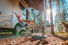 a woman sitting on a chair in front of a camper