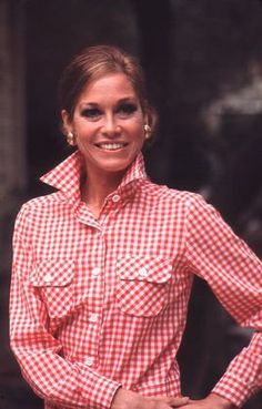 a woman in a red and white checkered shirt with her hands on her hips