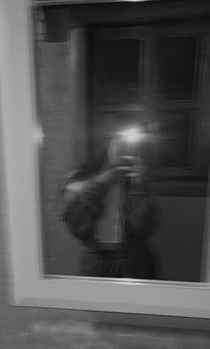 a blurry photo of a person taking a selfie in front of a window