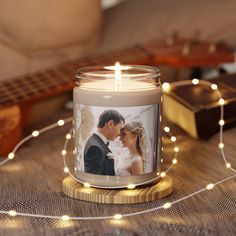 a candle with a photo on it sitting next to a string of lights and a guitar