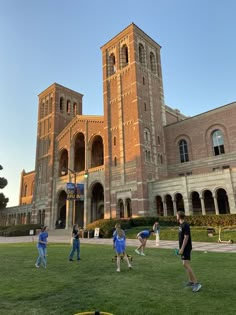 people playing frisbee in front of a large building