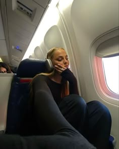 a woman sitting on an airplane talking on her cell phone