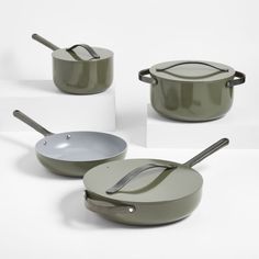 four pots and pans with spoons sitting on top of each other in front of a white background