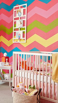 a baby's room with pink, yellow and green chevrons on the wall