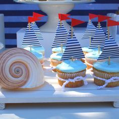 cupcakes with blue frosting and sailboats on them are sitting on a table