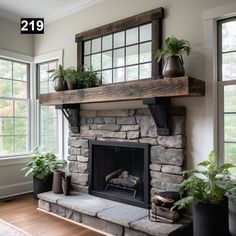 a stone fireplace with potted plants on the mantle and windows in the back ground