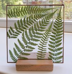 a green fern leaf cut out on a piece of wood in front of a window