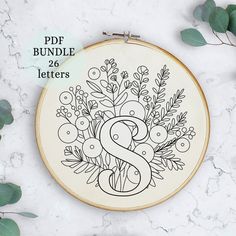 an embroidery pattern with the letter s on it and some plants in front of it