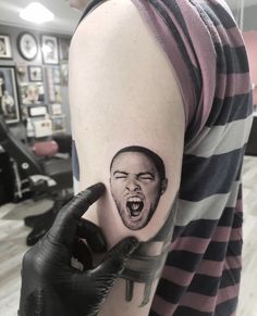 a person with a tattoo on their arm holding up his hand and making a face