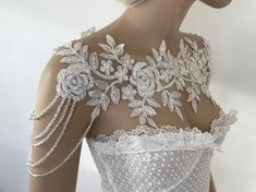 the back of a woman's wedding dress with beading and flowers on it