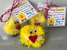 two yellow stuffed animals sitting on top of a wooden table next to a sign that says hug monster