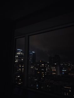 the city lights are lit up at night from an empty room with a large window