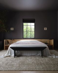 a large bed sitting under a window next to a white rug on top of a wooden floor