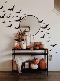 halloween decorations with bats on the wall and pumpkins in front of it, along with a mirror