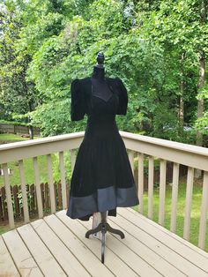 This is a vintage dress in good/ fair vintage condition. There are no smoke, no mold, and no pet odors. There is wear, including a big hole on the lining, some wear to the velvet, loose threads, and spots on the dress. The dress is velvet like material,  and has shoulder pads. The dress is tagged a size 6. Please see photos for condition and zoom in if necessary. Approximate measurements: Shoulder to Shoulder- 13 Inches Across Pit to Pit- 16 Inches Across Waist- 13.5 Inches Across Vintage Short Sleeve Dress For Costume Party, Fitted Puff Sleeve Dress For Costume, Vintage Knee-length Dress With Fitted Bodice, Black Retro Dress For Vintage Events, Vintage Dress With Fitted Bodice And Short Sleeves, Fitted Puff Sleeve Costume Dress, Retro Dresses For Vintage Events In Fall, Lined Short Sleeve Dress For Vintage Events, Vintage Midi Dress With Fitted Bodice