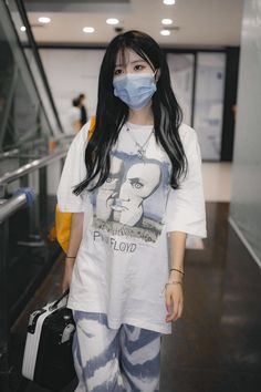 a woman wearing a face mask walking down an escalator