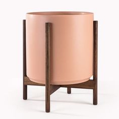 a pink planter sitting on top of a wooden stand