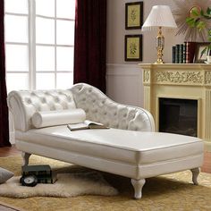 a white leather chaise lounge chair in front of a fire place with a rug on the floor