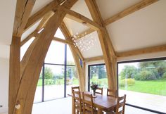 the dining room table is surrounded by wooden beams and glass doors that lead out to an outdoor garden