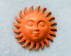 an orange plastic sun face on a blue towel with one eye open and the other half closed