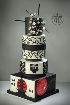 a three tiered cake with black and white designs on the sides, decorated with flowers