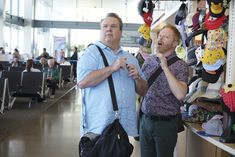 two men standing next to each other in a room with lots of stuffed animals on the shelves