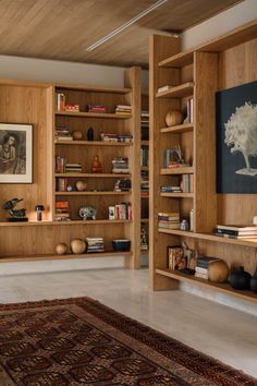 a living room filled with wooden bookshelves next to a painting on the wall