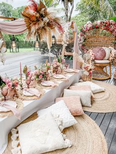 a table set up with pink and white flowers, feathers and place settings on it