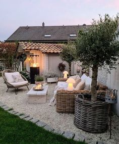 an outdoor living area with wicker furniture and lights on the side of the building