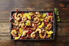 shrimp and pineapple kabobs on a baking sheet with garnishes