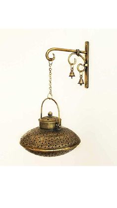 an old fashioned wall light hanging from a hook on the side of a white wall