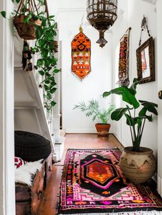 a hallway with plants and rugs hanging from the ceiling, along with potted plants