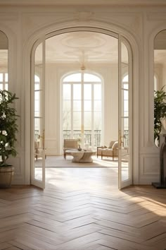 an open door leading into a living room filled with furniture and potted plants on top of hard wood flooring