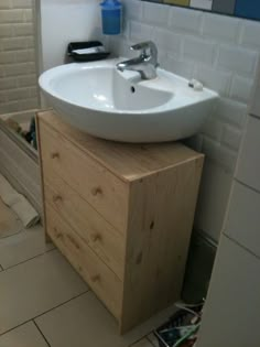 a white sink sitting on top of a wooden cabinet next to a mirror in a bathroom