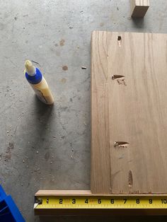 a piece of wood is being worked on with a ruler and glue bottle next to it