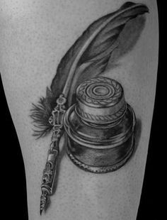 a black and white photo of a feather quill with ink pen on the thigh