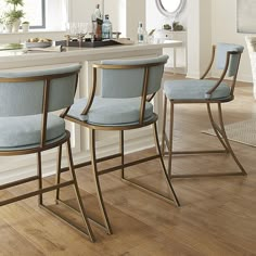 three blue chairs sitting on top of a hard wood floor next to a kitchen counter